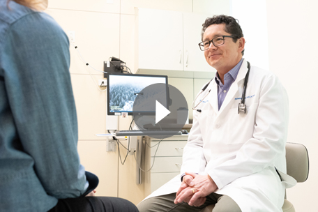 Video play button over image of Kaiser Permanente Colorado doctor talking with patient