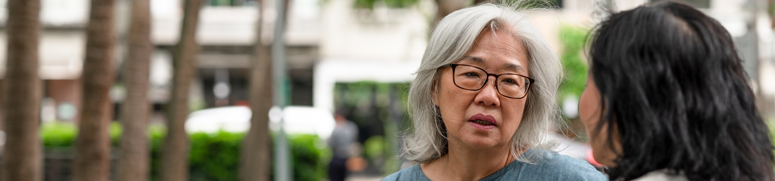 Two middle-aged people sitting in a park, having a serious conversation.