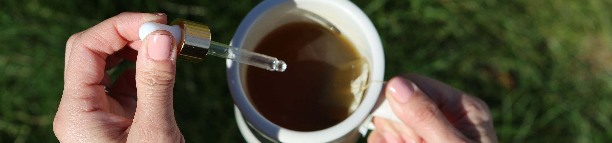 Person squirting CBD oil into a cup of tea