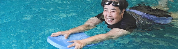 Adult swimming in pool with a kickboard