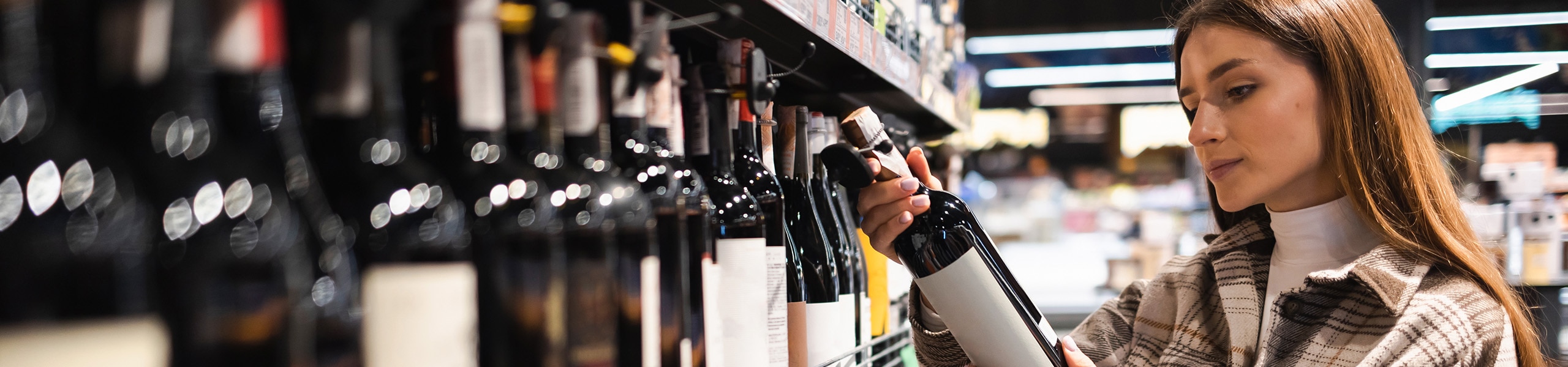 Person reading a wine label in a liquor store