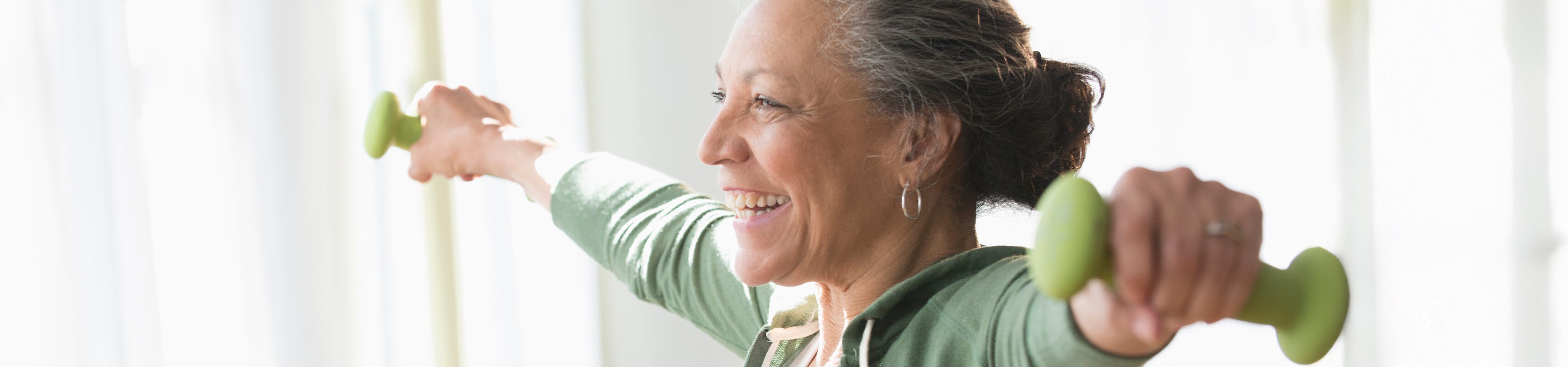 Smiling older person holding light weights