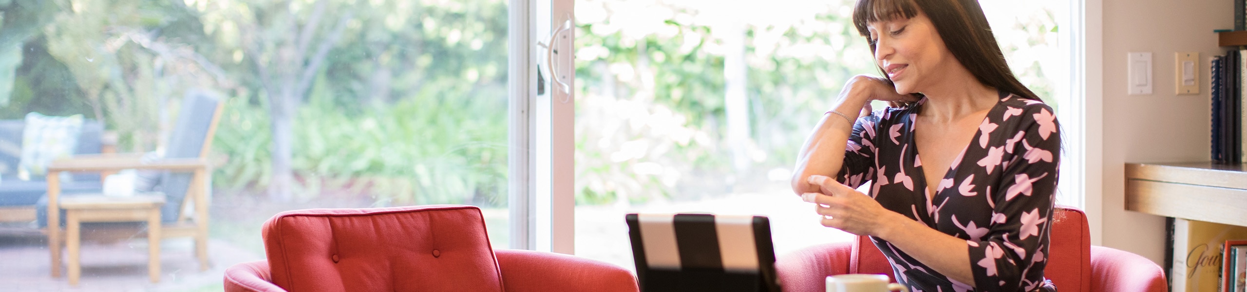 Woman sitting at home in front of laptop pointing to her elbow