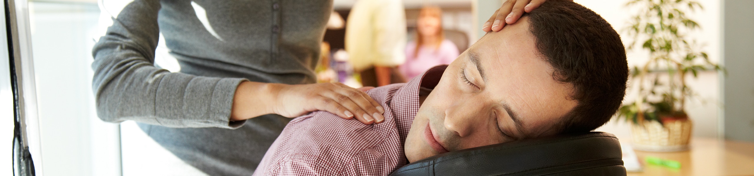 Massage therapist massages head and shoulders of a man on a massage chair