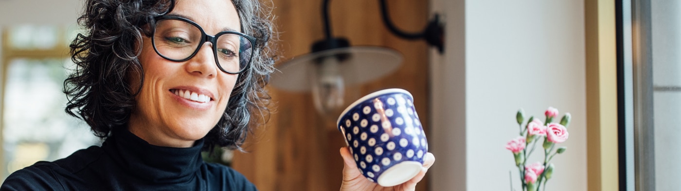 Person smiling and holding a coffee mug