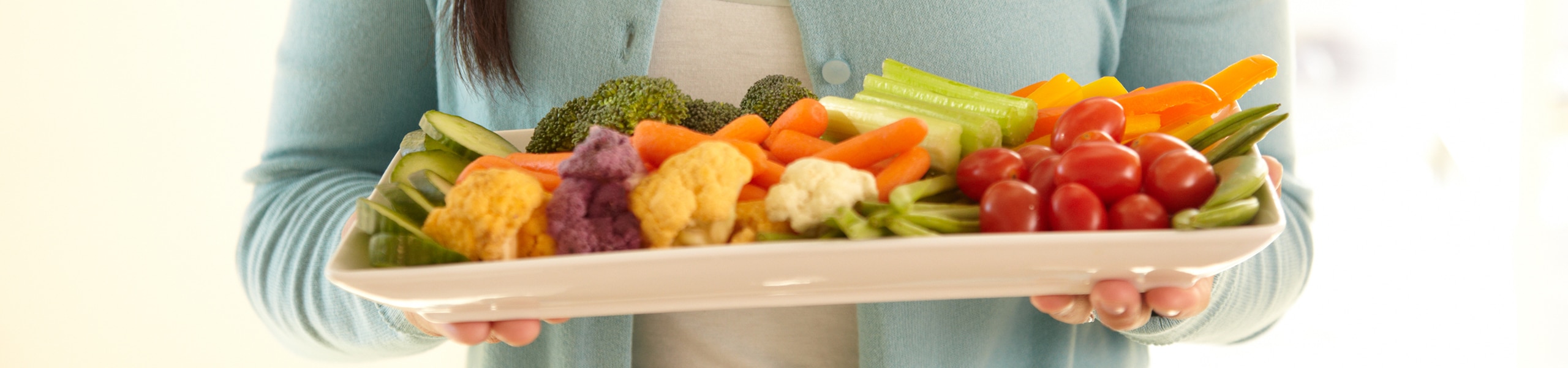 Person holding a platter of assorted raw vegetables
