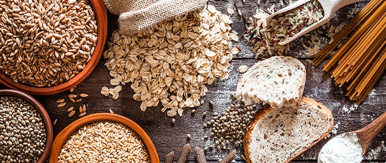 An array of grains and breads on a wooden surface