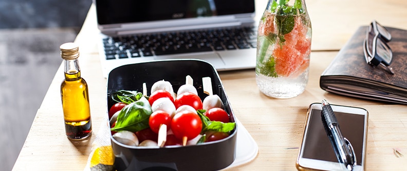 A healthy snack on a table next to a computer and a smartphone