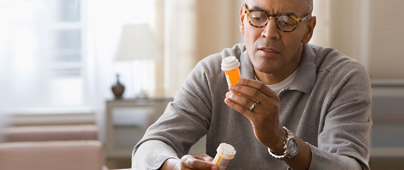 A man reads labels on a prescription bottle