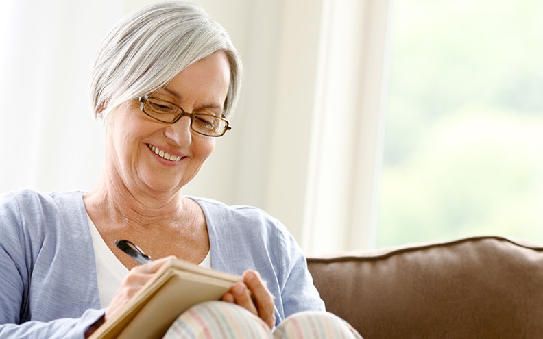 A smiling woman writes in a journal