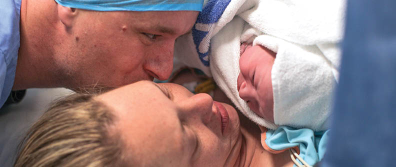 A husband and wife hold their newborn baby boy for the first time.