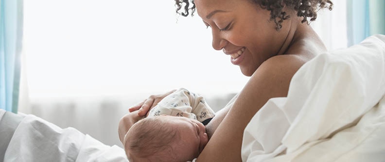 Mixed race mother nursing newborn baby.