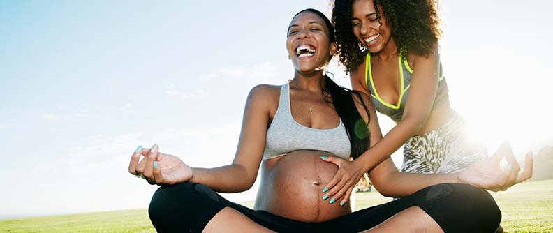 Pregnant woman in park doing yoga.