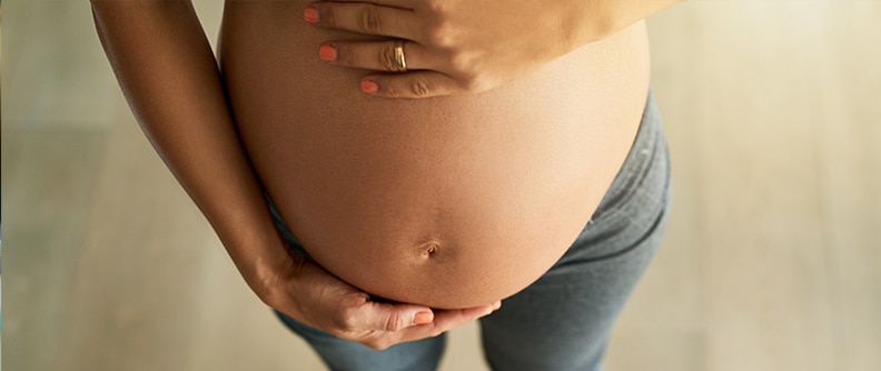 Cropped high angle shot of a pregnant woman weighing herself on a scale.