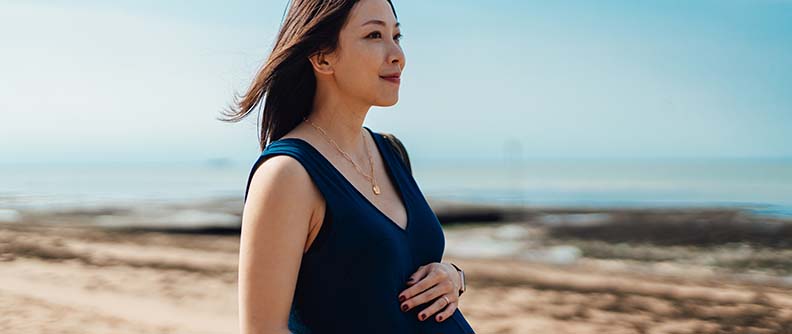 Pregnant woman having a walk by the beach.