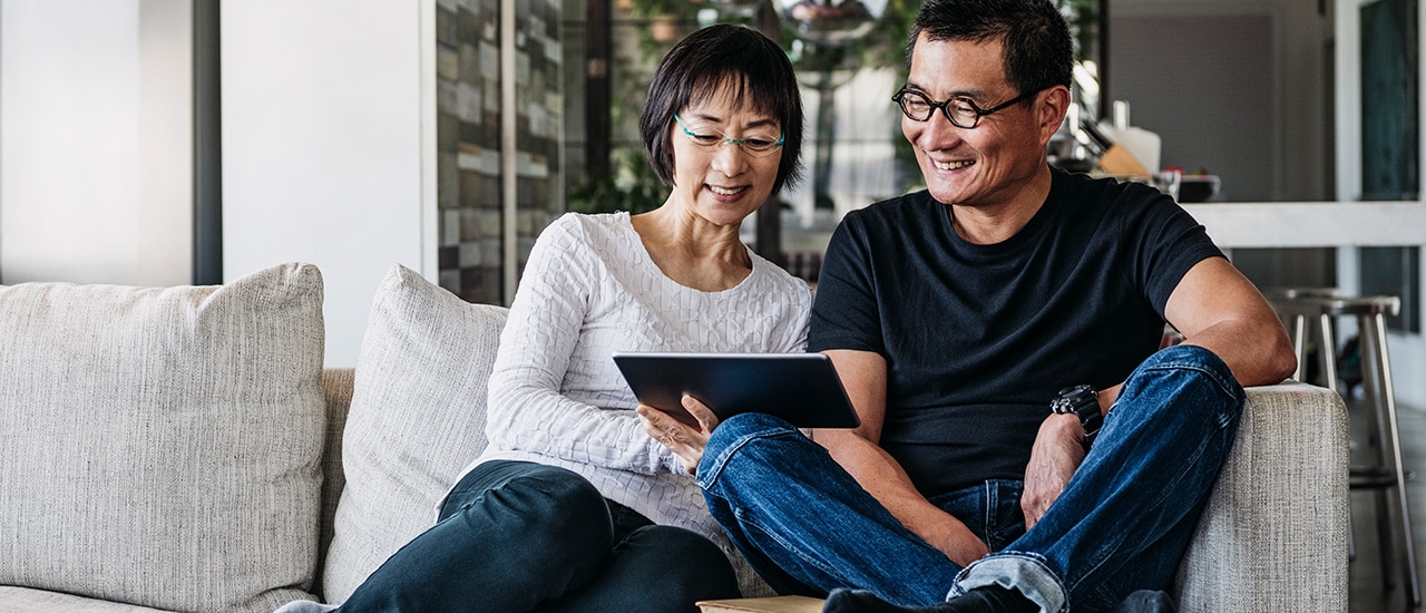 Older couple on couch looking at a tablet