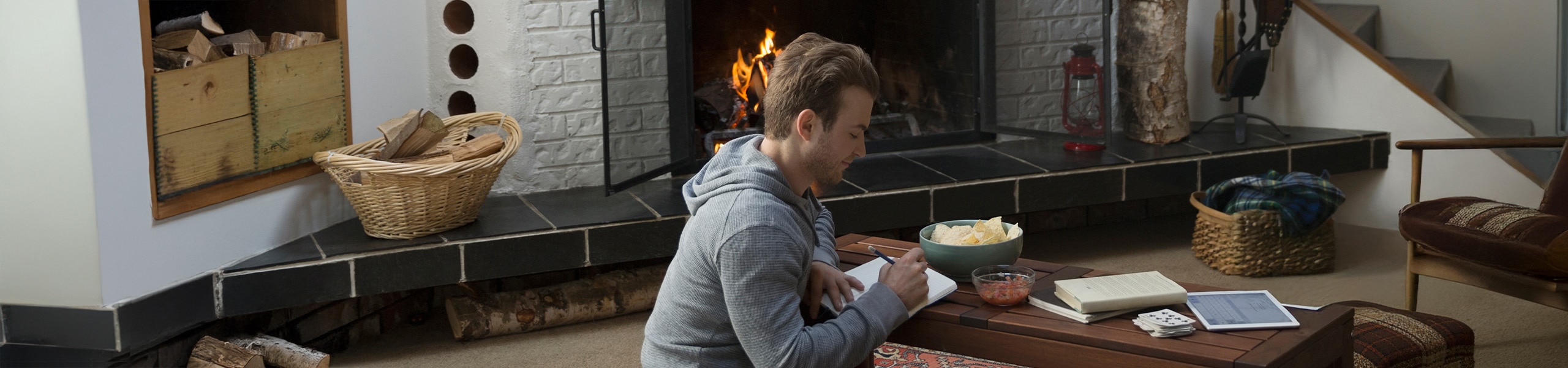 Person writing in a  journal by a fireplace