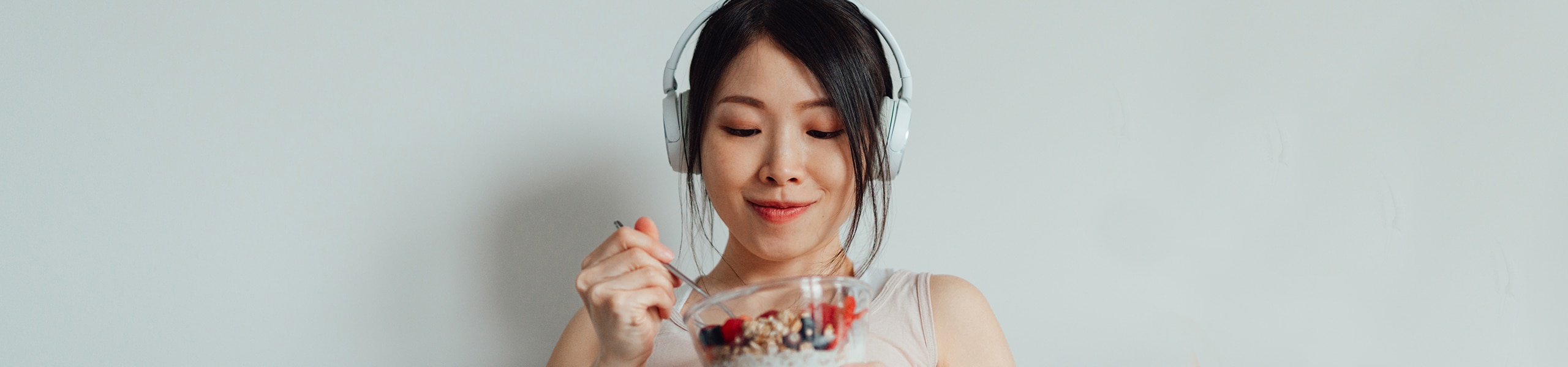 Person wearing headphones enjoys a bowl of yogurt and berries