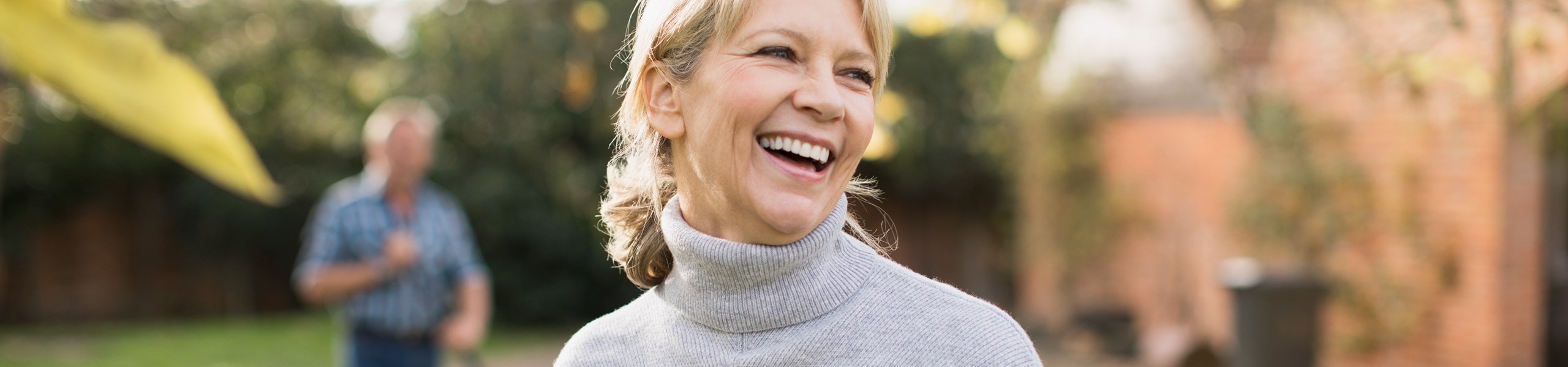 Woman wearing a turtleneck laughs outdoors