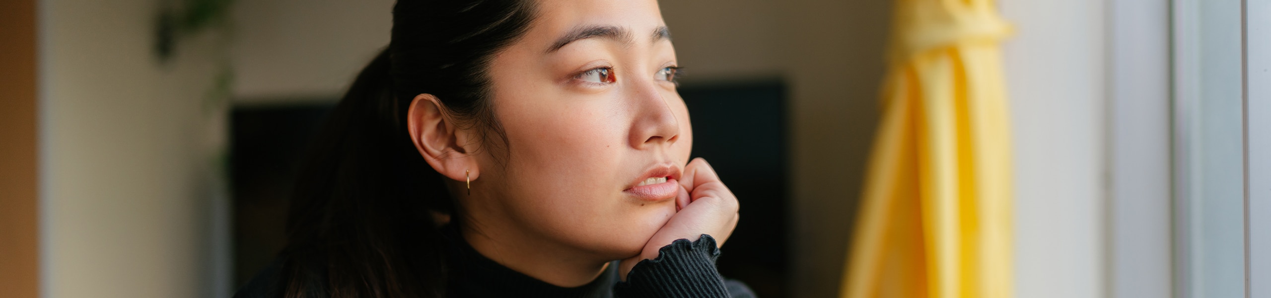 Young woman looking out a window and contemplating 