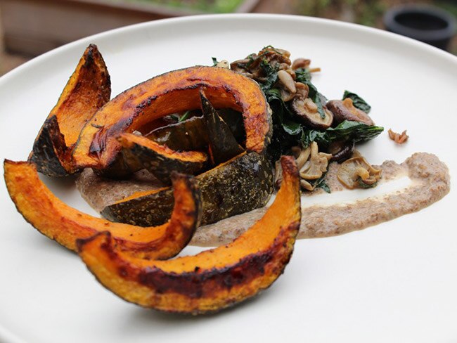 Roasted squash with mushrooms and kale on a white plate