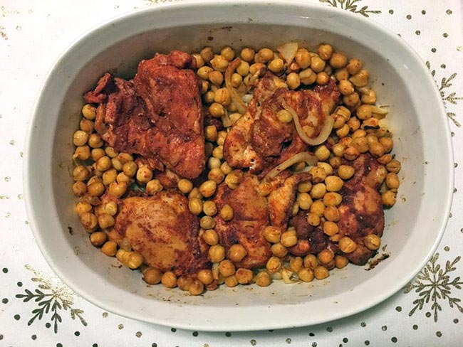 Paprika chicken with chickpeas in a white baking dish.