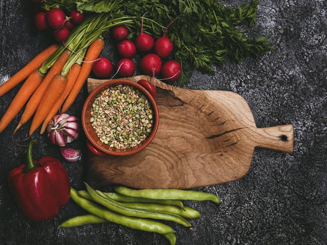 rustic cutting board surrounded with vegetable ingredients for vegan lentil soup
