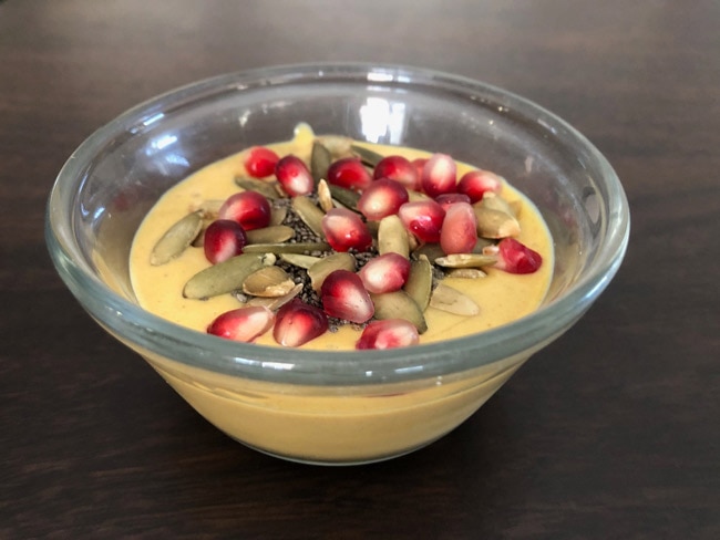 Puree of ingredients including cottage cheese, banana, pumpkin puree, and spices topped with seeds in glass bowl.
