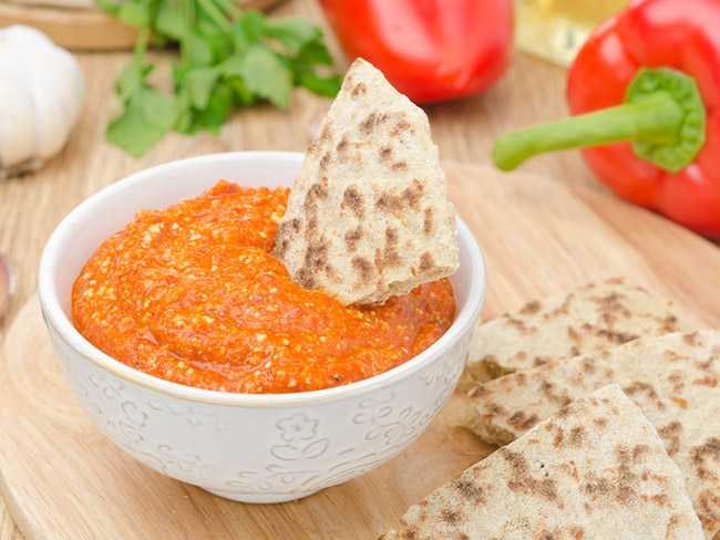 Roasted red pepper and almond dip with pita slices on the side.