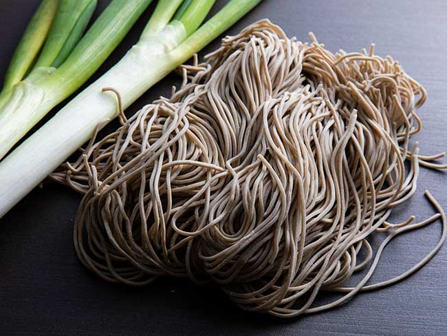 Fresh soba noodles with two stalks of bok choy on the side