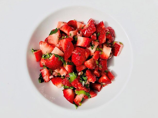 A white bowl filled with fresh strawberry salsa.