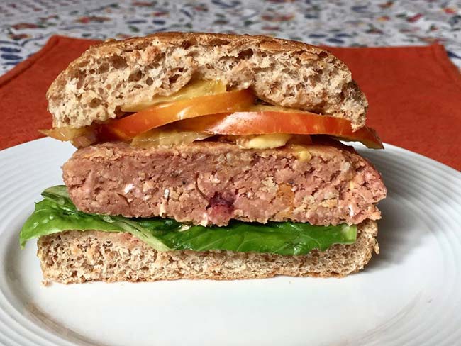 Half a meatless burger with lettuce and tomatoes on a whole wheat bun.
