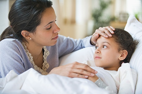 Parent resting their hand on sick child’s forehead