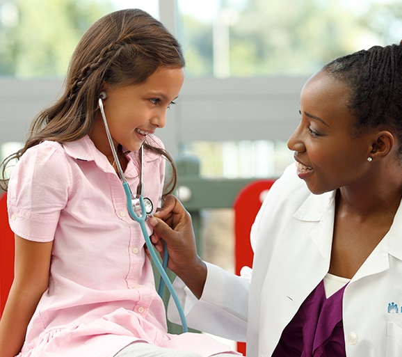 Doctor checking heartbeat of smiling child