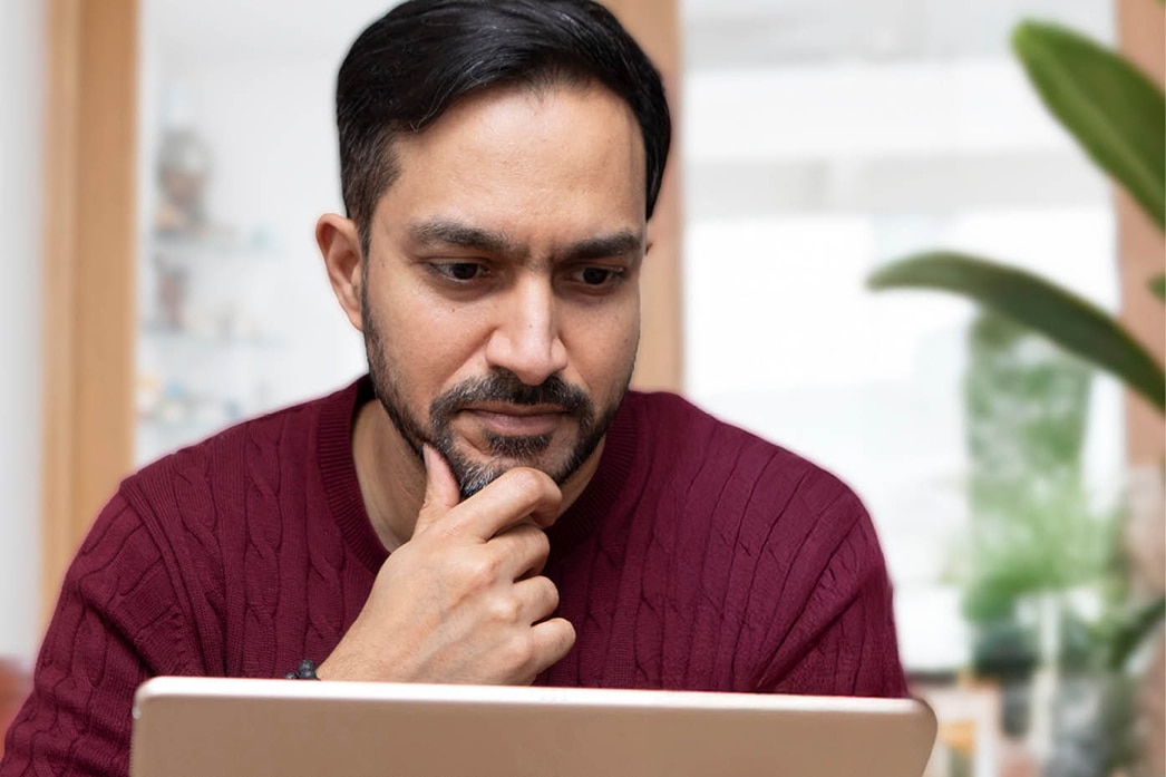 A thoughtful person reading a laptop screen