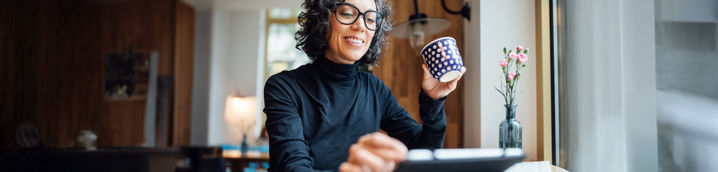 Person drinking coffee while looking at a tablet