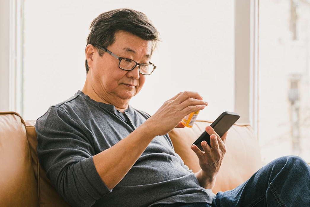 Person holding mobile device looking at prescription bottle