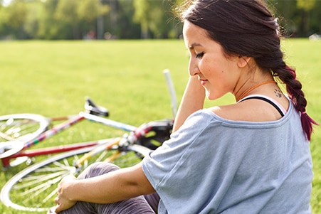 Person sitting on the grass next to a bicycle