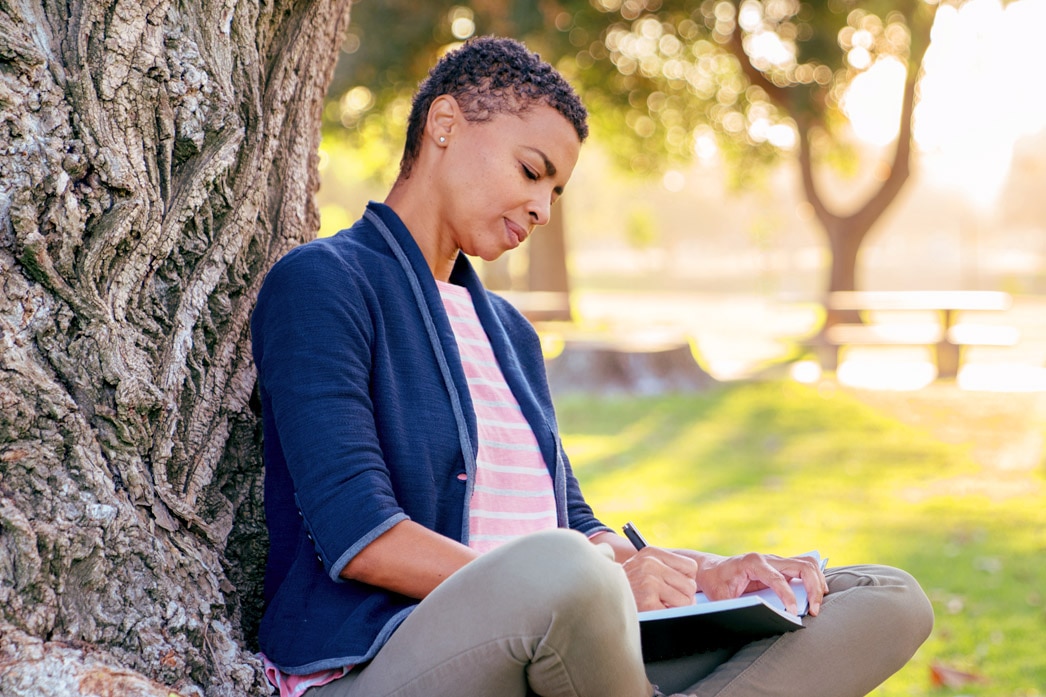 Person writing in a journal in a park