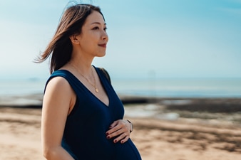 Pregnant person walking on the beach