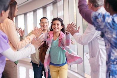 Child getting high-fives while leaving a hospital