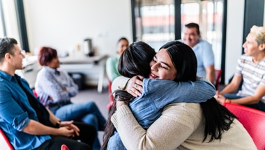 Two people hugging at a community group meeting