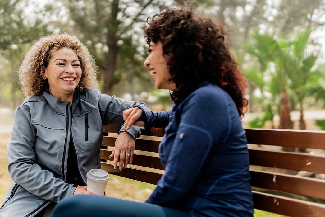 Friends laughing together on a park bench