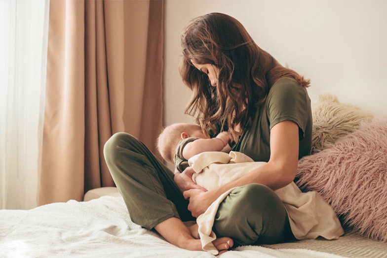 Parent breastfeeding baby on bed