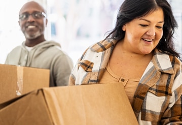 Smiling people holding moving boxes