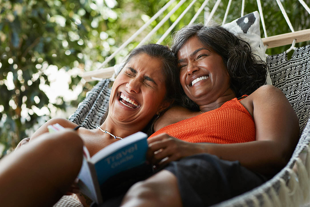 Two people laughing in a hammock