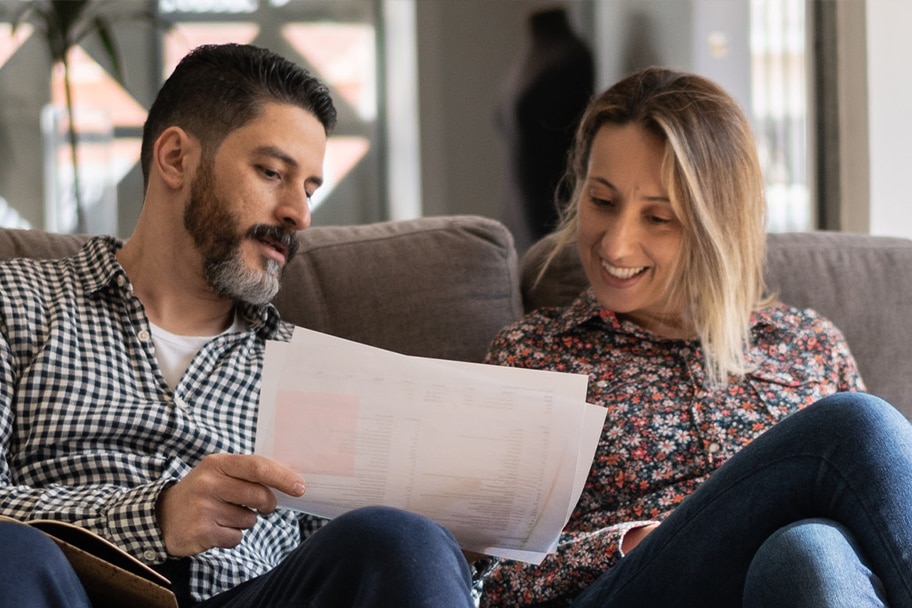 Two people sitting on a couch looking at a piece of paper