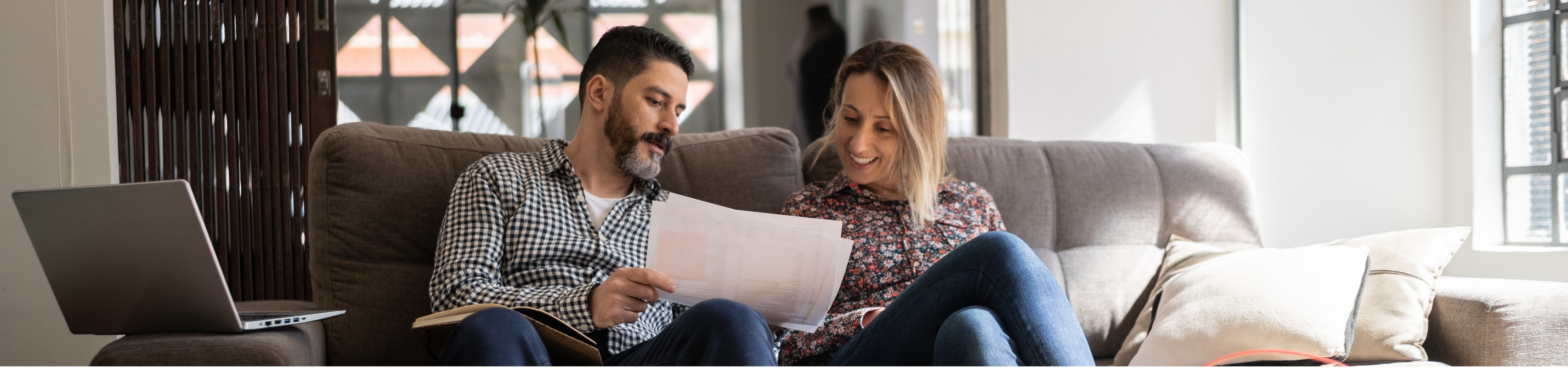 Two people sitting on a couch looking at a piece of paper