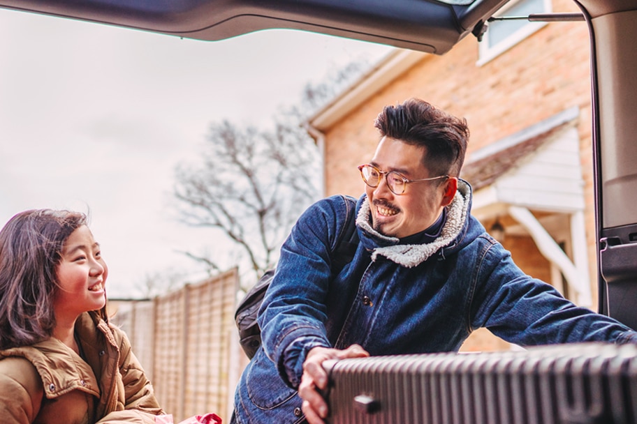 Two people smiling and moving luggage