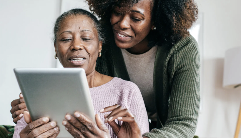 Person helping older person use a tablet 